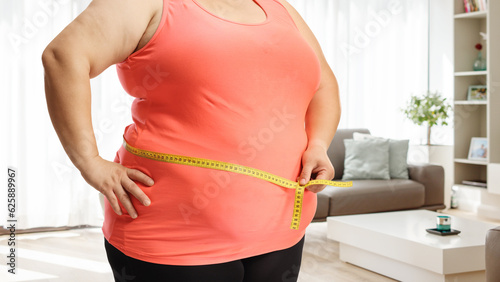 Overweight female torso measuring waist at home