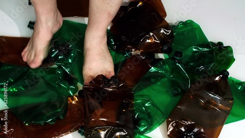 Feet trample on a lot of plastic bottles for disposal. The concept of help the environment from pollution with garbage. Hazardous plastic, not recyclable. Large multicolored plastic bottles destroyed