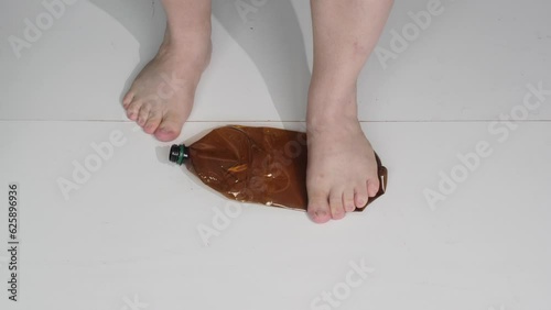 Feet trample on plastic bottles for disposal. The concept of helping the environment from pollution with garbage. Hazardous plastic, not recyclable. Large multicolored plastic bottles are destroyed.