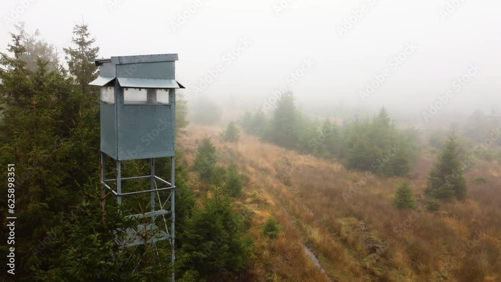 A drone pans to a watch tower in a forest filled with mist in Belgium. A drone pans to a watch tower in a forest filled with mist in Belgium.