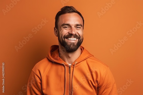 smiling man in orange hoodie looking at camera isolated on orange photo