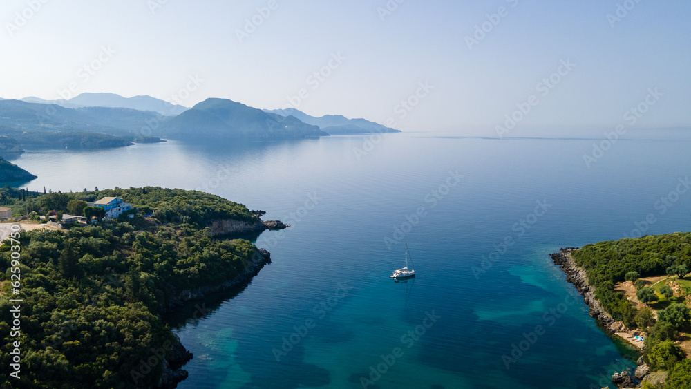 Aerial drone ultra wide panoramic photo of luxury sailboat anchored in tropical exotic island with crystal clear turquoise sea and pine trees