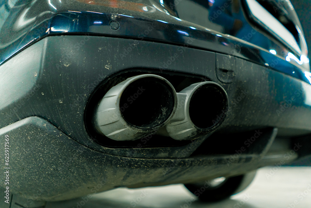 Close-up of the dirty exhaust pipe of a luxury car before the car wash and detailing into the boxing area