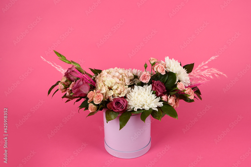 Bouquet of flowers on a pink background. A bouquet in a pink cardboard box. Box with a bouquet of flowers. Copy space.