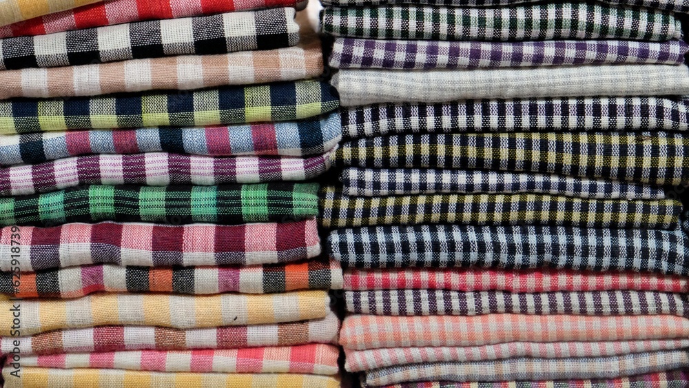 Close-up shot showcasing the vibrant assortment of stacked multicolored fabrics forming a picturesque background. Close-up shot showcasing the vibrant assortment of stacked multicolored fabrics forming a picturesque background.