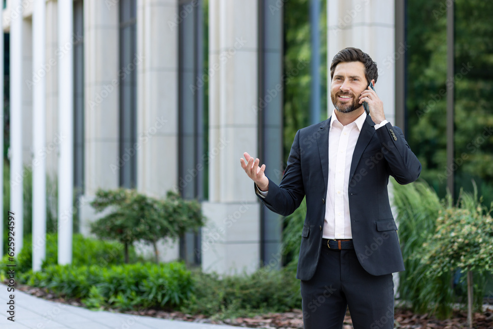 Mature successful boss talking on the phone, senior experienced businessman in business suit talking to clients using smartphone, man outside office building happy with achievement Mature successful boss talking on the phone, senior experienced businessman in business suit talking to clients using smartphone, man outside office building happy with achievement
