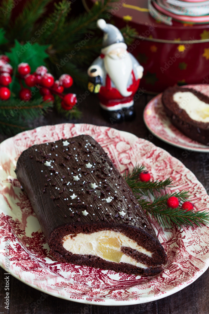 Chocolate roll stuffed with butter cream and pineapple on a Christmas background. Rustic style.