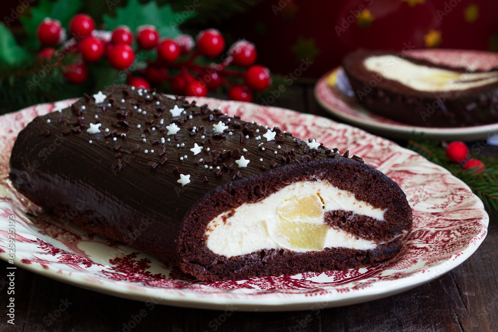 Chocolate roll stuffed with butter cream and pineapple on a Christmas background. Rustic style.