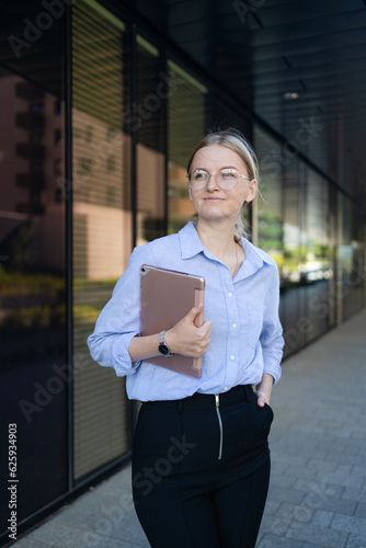 Young elegant professional leader Caucasian woman, female executive retail manager supervisor, small business owner wearing suit holding digital tablet standing outdoor looking at camera, portrait. © Shi 