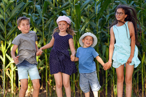 Children have fun jumping in front of a cornfield. Happy healthy childhood.