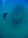 some divers exploring a small sunken ship in the caribbean sea