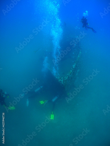some divers exploring a small sunken ship in the caribbean sea © gustavo