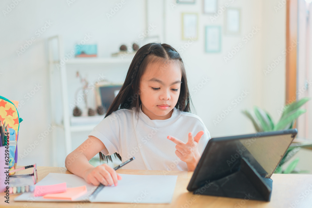 Asian school girl doing homework at laptop raising hand pointing finger . The girl does his homework. Home schooling.