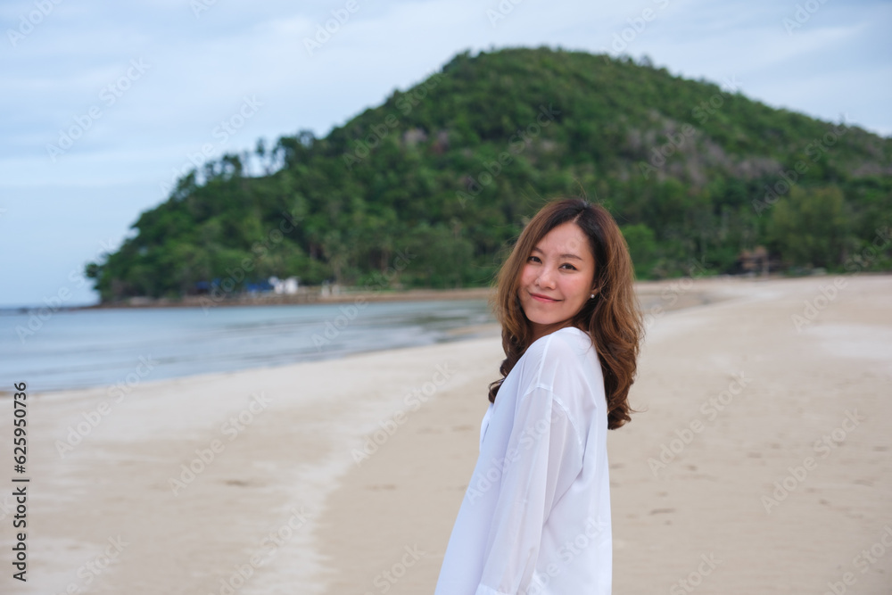 Portrait image of a beautiful young asian woman while strolling on the beach with the sea and blue sky Portrait image of a beautiful young asian woman while strolling on the beach with the sea and blue sky