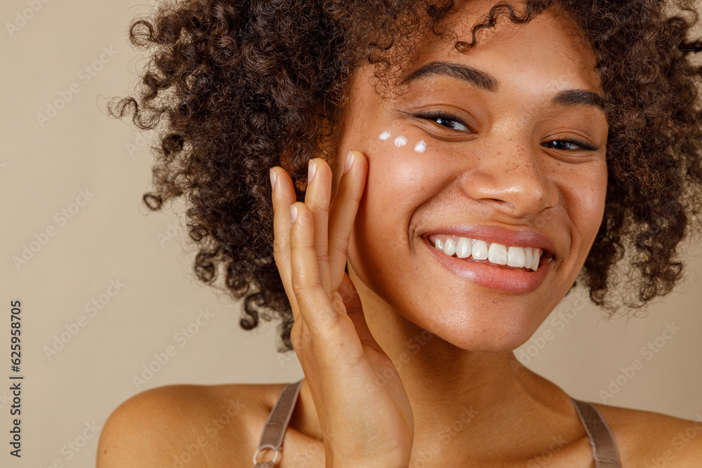 © Friends Stock - Young female model posing against beige wall