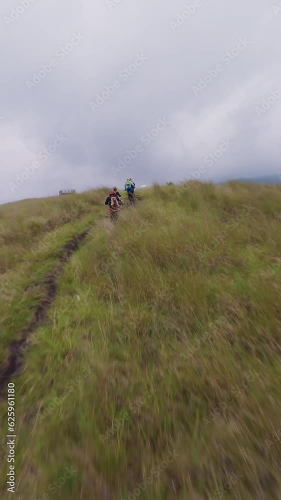 Vertical video 4k. Enduro motorbike riders group driving tour on mountain ridge enjoy freedom travel adventure aerial view. FPV sport drone shot motorcycle cross extreme autumn terrain cloudy valley Vertical video 4k. Enduro motorbike riders group driving tour on mountain ridge enjoy freedom travel adventure aerial view. FPV sport drone shot motorcycle cross extreme autumn terrain cloudy valley