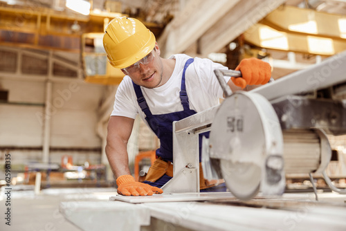 Fotografia Smiling male worker using sawing machine in workshop