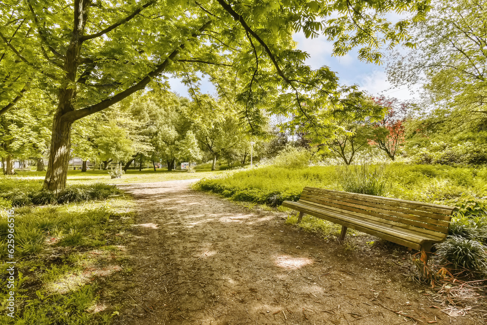 a bench in the middle of a park with trees and green grass on either side of the path that leads up to it