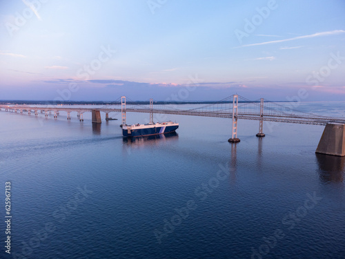 Foto An aerial photo of a Cargo Boat passing under the Chesapeake Bay Bridge in Annapolis Maryland during sunset