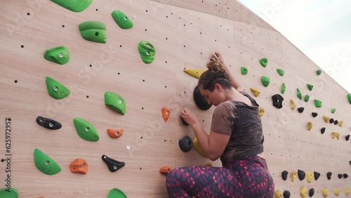 Adult woman climbing on a climbing wall in slow motion, Cinematic photo