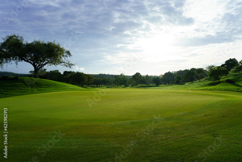 Fototapeta Naklejka Na Ścianę i Meble -  Golf green in the morning sun backlit against cloudy sky