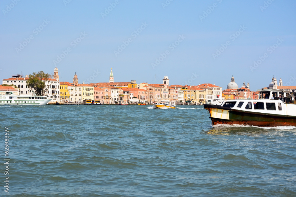 Small boats sail and transport tourists on the sea against the background of the picturesque architecture of Venice, Italy