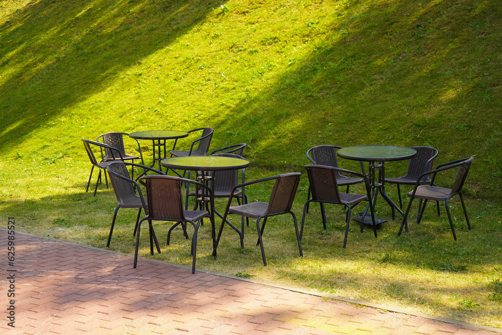 Brown chairs and round tables set in the garden at a cafe, outdoor zone, outside seating. Brown chairs and round tables set in the garden at a cafe, outdoor zone, outside seating.