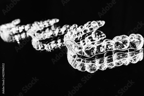 Invisible aligners retainers of teeth lie on the mirror on a black and white photograph