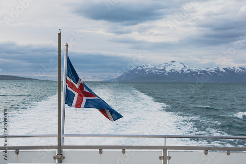 Flag of Iceland on a boat, with glacial mountains in the background