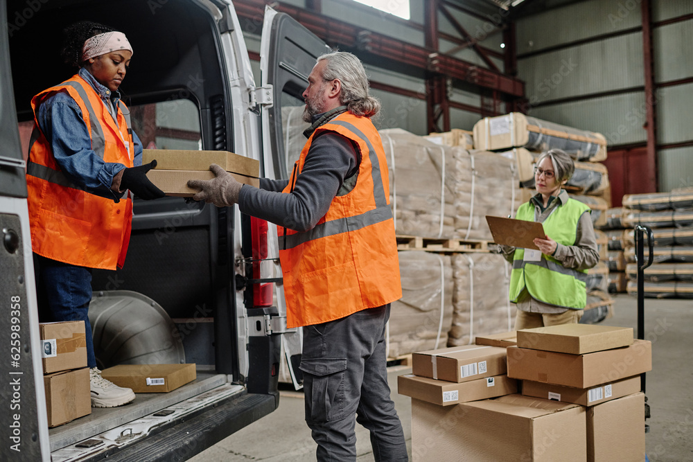 Warehouse workers loading cargo in truck with foreman controlling the working process in warehouse Warehouse workers loading cargo in truck with foreman controlling the working process in warehouse