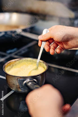 Chef hands cooking cheese sauce in the restaurant kitchen