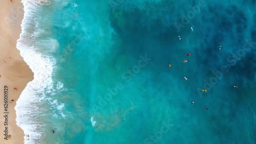 Top view of surfers in the ocean next to Bali beach. Surfing in the Indian Ocean