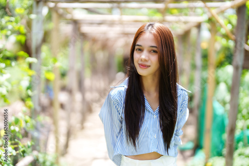 Asian women wear casual clothes, take walk-in garden, feel natural breezes in attractions that go relax on holiday in good weather, woman smiling at camera in good mood in by natural green forest.