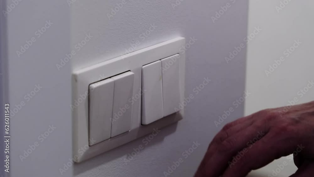 white light switch on a white wall. Turning off the light in the room.