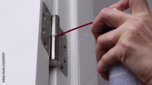 A man is oiling the door hinges. adjusting door hinge using lubricating oil.
