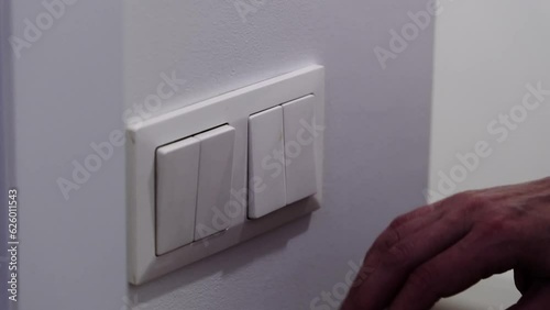 white light switch on a white wall. Turning off the light in the room.