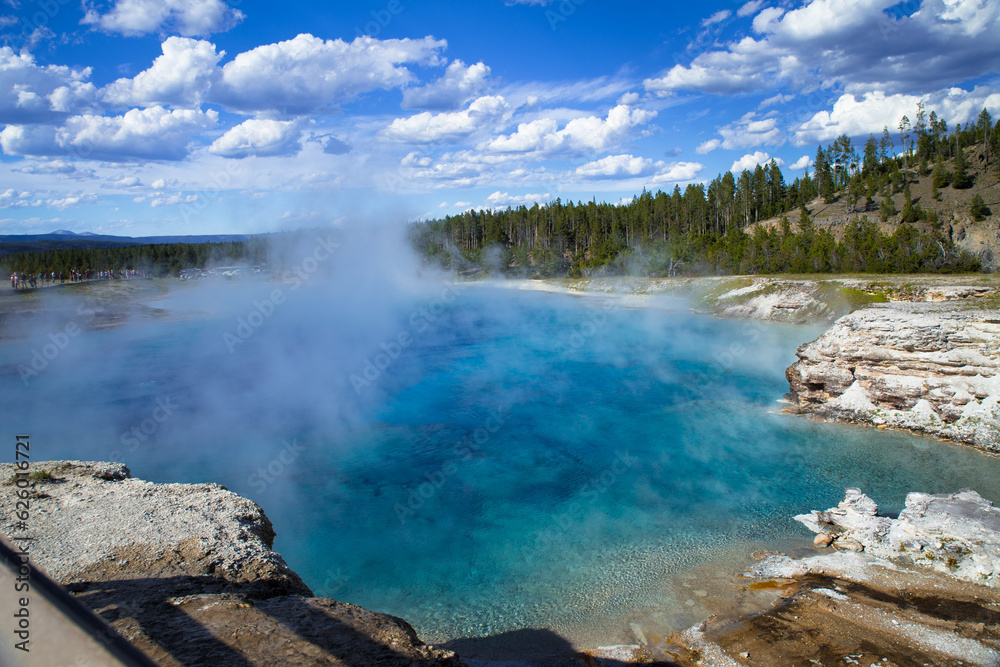 the blue hot spring with steam rising from water  in Yellowstone National Park