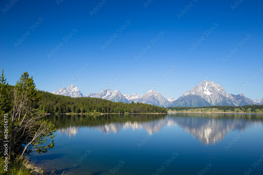  Grand Teton mountain range with pine forest and lake reflection in front