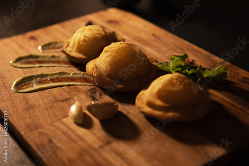 Venezuelan pastelitos street food, potato and cheese filling and salsa verde photo