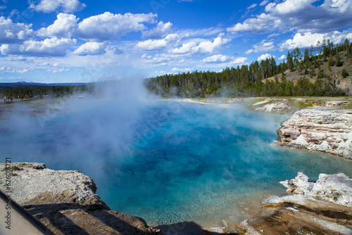 the blue hot spring with steam rising from water in Yellowstone National Park