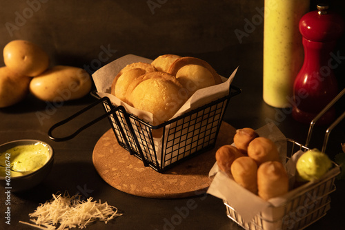 Venezuelan pastelitos and tequeños in a frying basket  with salsa verde photo