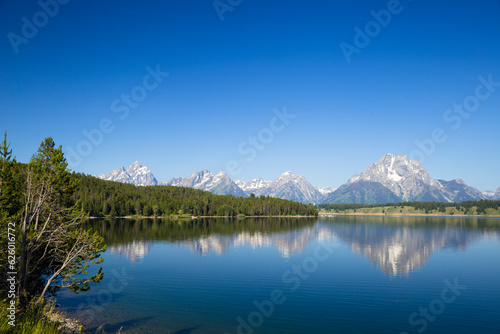  Grand Teton mountain range with pine forest and lake reflection in front © Echo