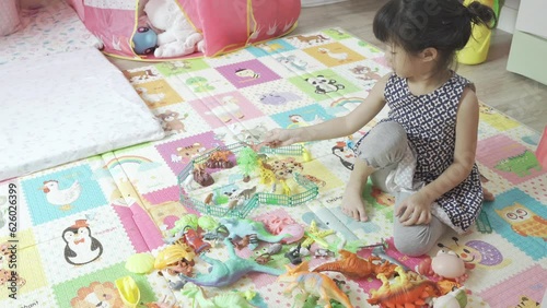 Little girl play anaimal and dinosaur and walk to pink tent find something in her play room.Home deco design. photo