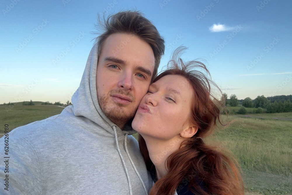 selfie of two lovers or best friends, guy and a girl hugging in nature, having fun