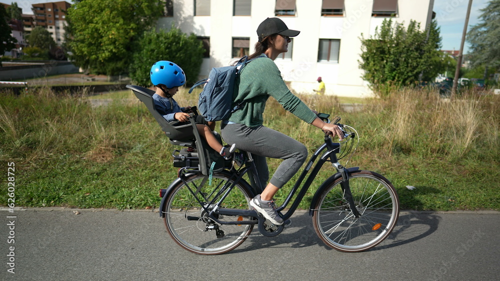 Parent riding bicycle with child sitting in back seat