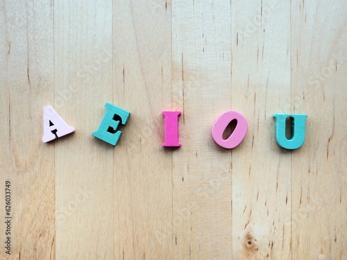 Aeiou uppercase vowels on a wooden background  photo