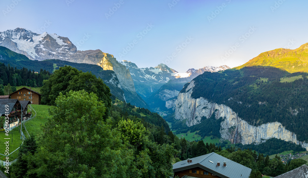 A panorama of a mountain range, blue skies and chalets in the Swiss alps in Switzerland