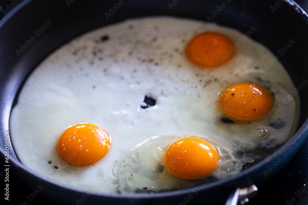 A portrait of multiple sunny side up eggs baking in a frying pan. The cook is creating a great breakfast, lunch or brunch. The egg white and the yolk is nicely separated. A portrait of multiple sunny side up eggs baking in a frying pan. The cook is creating a great breakfast, lunch or brunch. The egg white and the yolk is nicely separated.