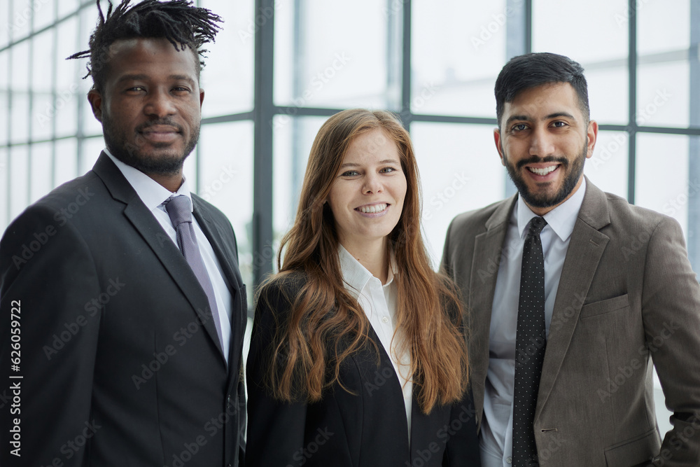 Three professionals in formal suits standing for camera indoors and smiling. Corporate friendship concept Three professionals in formal suits standing for camera indoors and smiling. Corporate friendship concept