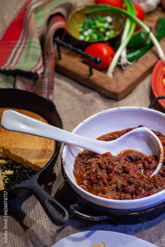 Homemade chili dinner with cornbread and ingredients.